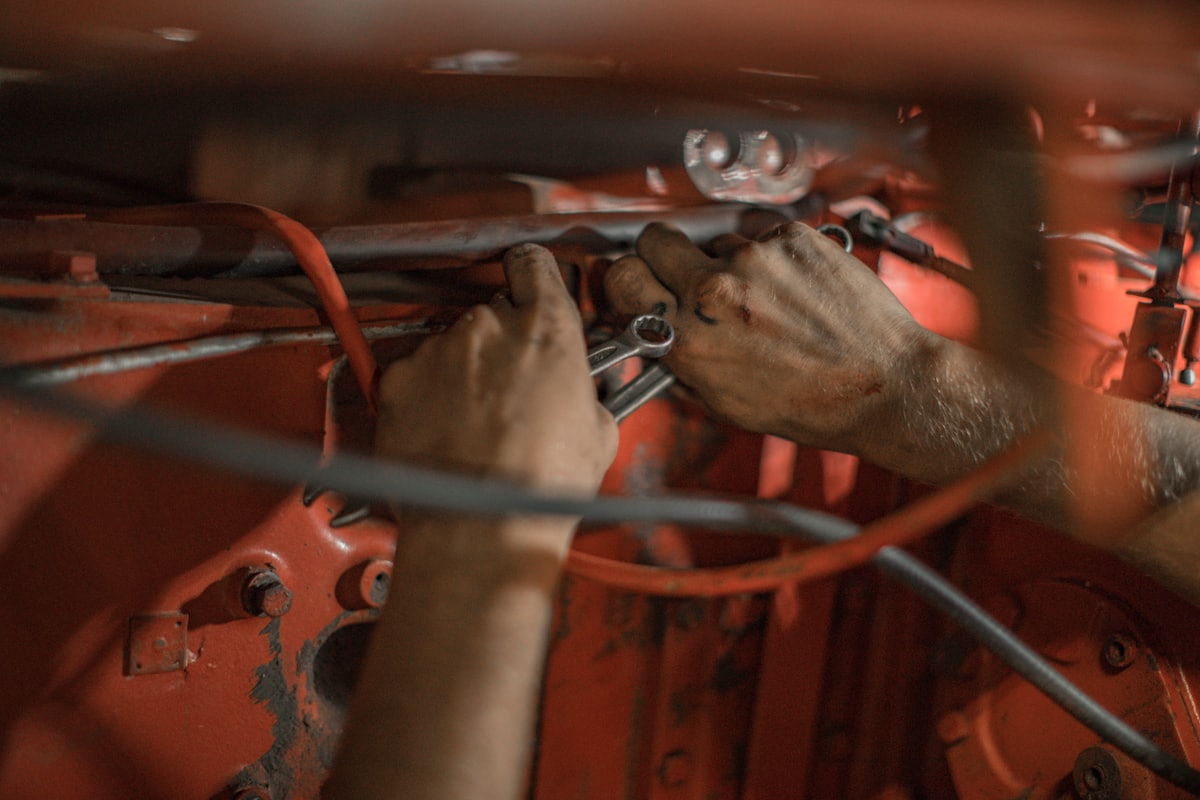 Hände eines Schraubers der Werkstatt Freitag bei der Arbeit an einem älteren Motor.